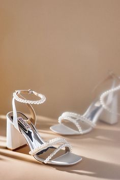 two pairs of white high heeled shoes with pearls on the toes and ankle straps