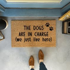 a door mat that says the dogs are in charge we just live here with someone standing next to it