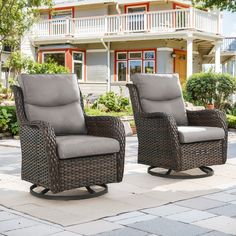 two wicker chairs sitting in front of a house on a brick patio with stone pavers