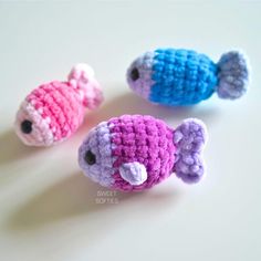 three small crocheted fish sitting next to each other on a white counter top