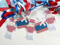 some paper cutouts are hanging from ribbons on a white surface with red, white and blue streamers