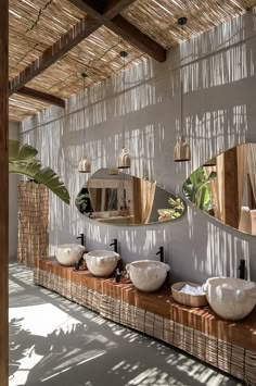 a bathroom with two sinks and mirrors on the wall next to each other in front of a bamboo roof