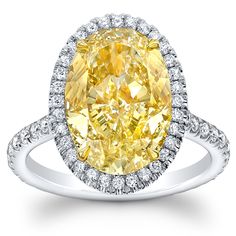 a fancy yellow diamond ring with diamonds around the band and an oval center surrounded by round cut