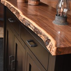 a wooden counter top sitting on top of a black cabinet next to a light bulb