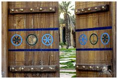 two wooden doors with blue and white designs on the outside, one has a palm tree in the background