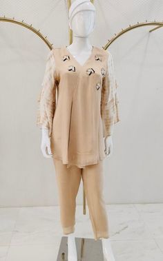 A peach colored kurta and palazzo set, curated for a casual evening affair, is fashioned from luxurious fabric to guarantee comfort. The short kurti, adorned with embroidered buttis scattered around the neck and featuring elbow-length 3 tier sleeves, exudes an understated elegance. The ensemble is impeccably completed by plain straight pants in matching colors, presenting a cohesive and sophisticated look.  Note: Colors may slightly vary due to photographic lighting. Please contact us if you hav Summer Straight Kurta With Set-in Sleeves, Designer Spring Kurta With Set-in Sleeves, Designer Wear Spring Kurta With Set-in Sleeves, Festive Spring V-neck Palazzo Set, Designer Straight Kurta Pant Set For Spring, Designer Spring Straight Kurta Pant Set, Spring Designer Pant Set With Straight Kurta, Designer V-neck Sets For Summer, Summer Festive Tunic Palazzo Set