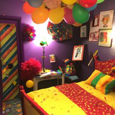 a bedroom decorated in bright colors with balloons hanging from the ceiling and colorful bedding