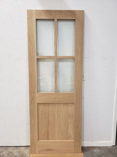 a wooden door with frosted glass on the top and bottom panel, in front of a white wall