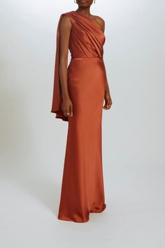 Fluid satin fit-to-flare gown bias draped one-shoulder dress. Shown in Copper. Satin Dress One Shoulder, Gold One Shoulder Gown, Copper Evening Dress, One Shoulder Orange Dress, One Shoulder Silk Dress, Copper Formal Dress, One Shoulder Satin Dress, Satin One Shoulder Dress, One Shoulder Dress Formal