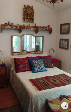 a bed sitting in a bedroom next to a dresser with two mirrors on top of it