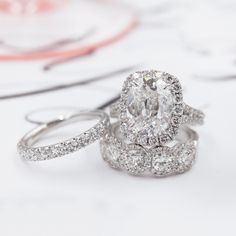 two wedding rings with an oval diamond surrounded by smaller diamonds