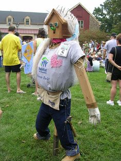 a man dressed up as a scarecrow in a yard with other people standing around