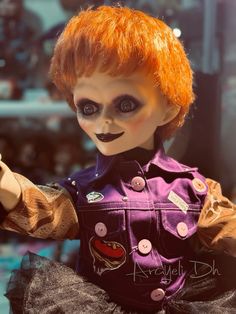 a doll with red hair and makeup holding a cell phone