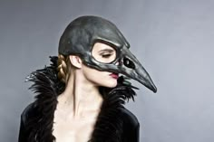 a woman wearing a bird mask with feathers on her head