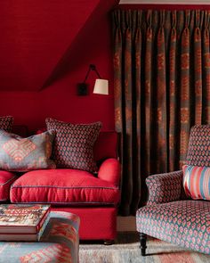 a living room with two couches and a chair in front of a red wall