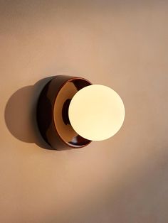 a light that is on the wall next to a brown wall mounted fixture with a white ball