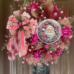 a wreath decorated with pink flowers and a santa clause on the front door for christmas