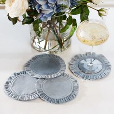 blue and white flowers in a glass vase with coasters