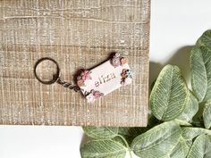 a keychain that is sitting on top of a piece of wood next to a plant