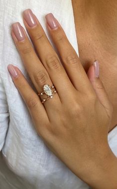 a woman's hand with a diamond ring on her left hand, wearing a white shirt