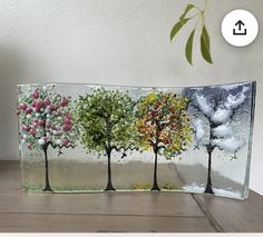 three trees are depicted in this handmade glass art piece, which is displayed on a table