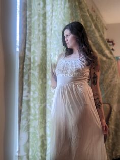 This enchanting lace and nylon nightgown exudes old Hollywood glamour. The bustline is completely lace, trimmed with ribbon to make a flattering emphasis on the bust. This white 1950s nightgown by Blue Swan would be stunning for the vintage bride! Overall excellent condition with no noted flaws. Labeled a size 36, best for medium/large. Nylon has good stretch! Measurements:  Bust 36"-taught 40" Waist 30"-34" Hips 48"  Length 54" Sheer Coquette Bedtime Dresses, Flirty Lace Trim Slip Dress For Daywear, Coquette Lace Trim Slip Dress For Daywear, Fitted Lace Trim Nightgown For Wedding, Vintage Lace Dresses For Wedding Night, Vintage Wedding Night Dress With Lace Work, Sheer Lace Slip Dress For Wedding, Lace Patchwork Slip Dress For Wedding, Vintage Nightgown With Delicate Lace For Wedding Night