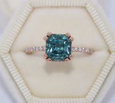 a fancy ring with an aqua blue diamond surrounded by white and rose gold pave