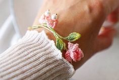 a close up of a person wearing a bracelet with flowers on it