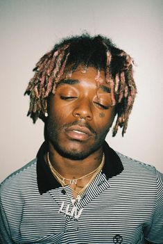 a man with dreadlocks is looking down at his cell phone while wearing a striped shirt