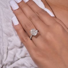 a woman's hand with a diamond ring on her finger and white manicured nails