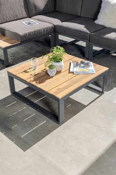 a wooden table sitting on top of a cement floor next to two couches and a coffee table