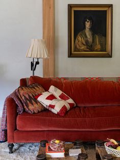 a living room with a red couch and coffee table in front of a painting on the wall