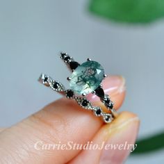 a person is holding a ring with an aqua green stone in it's center