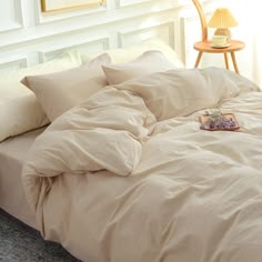 an unmade bed with white sheets and pillows