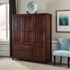 a living room with a chair and armoire in front of a window that has a painting on the wall