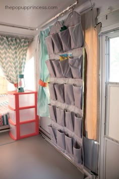 a room with a bed, window and curtains on the wall next to a shelf