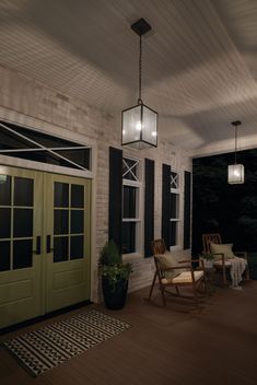 a porch with rocking chairs and lights on the ceiling