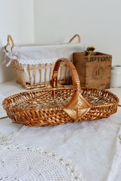 two wicker baskets sitting on top of a table next to boxes and doily