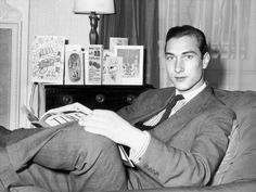 a man in a suit and tie sitting on a couch with his feet propped up