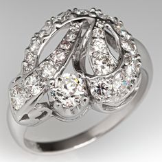 This lovely circa 1950s ring features a ribbon design and is accented with one (1) old European cut diamond set into a four-prong head and twenty-three (23), bead set, round brilliant/single cut diamonds. The ring measures 15.3mm at the top, rises 7.9mm above the finger, tapering to 2.0mm wide and 0.9mm thick at the base of the shank. This ring is currently a size 8. Vintage 14k White Gold Cluster Ring For Formal Occasions, Vintage Diamond Jewelry For Anniversary, Estate Diamond Jewelry For Formal Occasions, Estate White Gold Diamond Ring For Anniversary, Estate Style White Gold Diamond Ring For Anniversary, Estate Diamond Ring For Formal Occasions, Vintage Cubic Zirconia Rings For Anniversary, Estate Style Diamond Ring For Formal Occasions, Estate Diamond Ring With Accents For Wedding