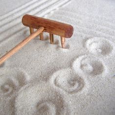 a wooden bench sitting on top of a white sand covered beach next to tracks in the sand