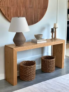 a wooden table with two baskets underneath it and a lamp on the side next to it