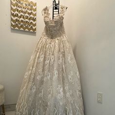 a white dress hanging on a wall next to a painting and chair in a room