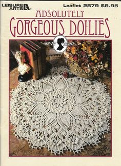 the front cover of an old crocheted doily pattern with a doll sitting on it