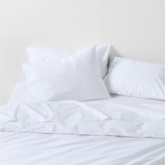 a bed with white sheets and pillows on it