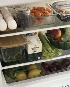 an open refrigerator filled with lots of fresh fruits and vegetables next to eggs in containers