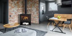 a living room with a fire place next to a dining table and chairs in front of a brick wall