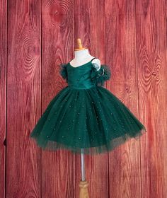 Little Darln Boutique  Our enchanting Knee Length flower girl dresses are sure to turn heads! This beautiful elegant dress is handmade, the bodice consists of Hunter Green satin with a layer of pearl tulle, followed by spaghetti straps and of the shoulder tulle sleeves. The back of the dress has a zipper for closure. The skirt consists of 4 Hunter Green layers of tulle with the top layer consisting of pearl beads. The fifth layer is made of lining with crinoline for fullness.  This dress is perfect for any occasion!  Dress Is Pictured with a petticoat NOT INCLUDED https://www.etsy.com/listing/1316417982/white-knee-length-petticoat-wedding?click_key=41cb8b0ae4587efa582b0a433f3f5e0cde12aec0%3A1316417982&click_sum=af1df37b&ref=shop_home_active_1 Visit our store, more items to come!  https://w Elegant Christmas Tutu Dress In Tulle, Elegant Christmas Tulle Tutu Dress, Elegant Tulle Holiday Dress For Festive Occasions, Fitted Tutu Dress For Christmas Fancy Dress, Fitted Christmas Tutu Dress For Fancy Dress, Elegant Festive Tulle Princess Dress, Fitted Tulle Princess Dress For Christmas, Elegant Green Pageant Dress For Dress-up, Elegant Tulle Ball Gown For Christmas