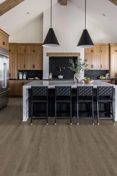 a large kitchen with wooden floors and white walls, has an island in the middle