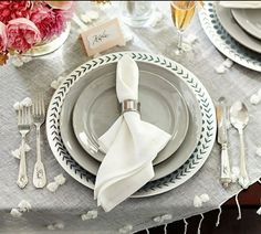 a table set with place settings, silverware and flowers